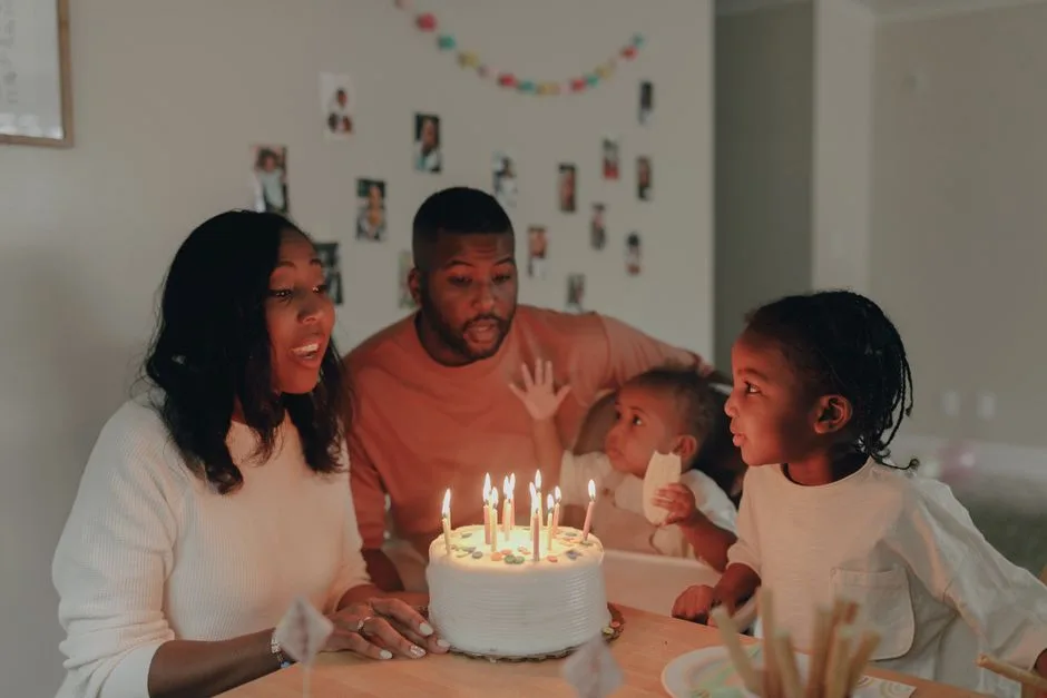A loving family celebrates a child's birthday with cake and candles indoors.