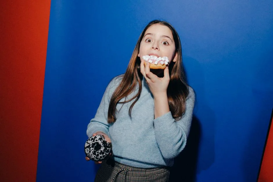 Girl having fun with doughnuts against vibrant blue background.