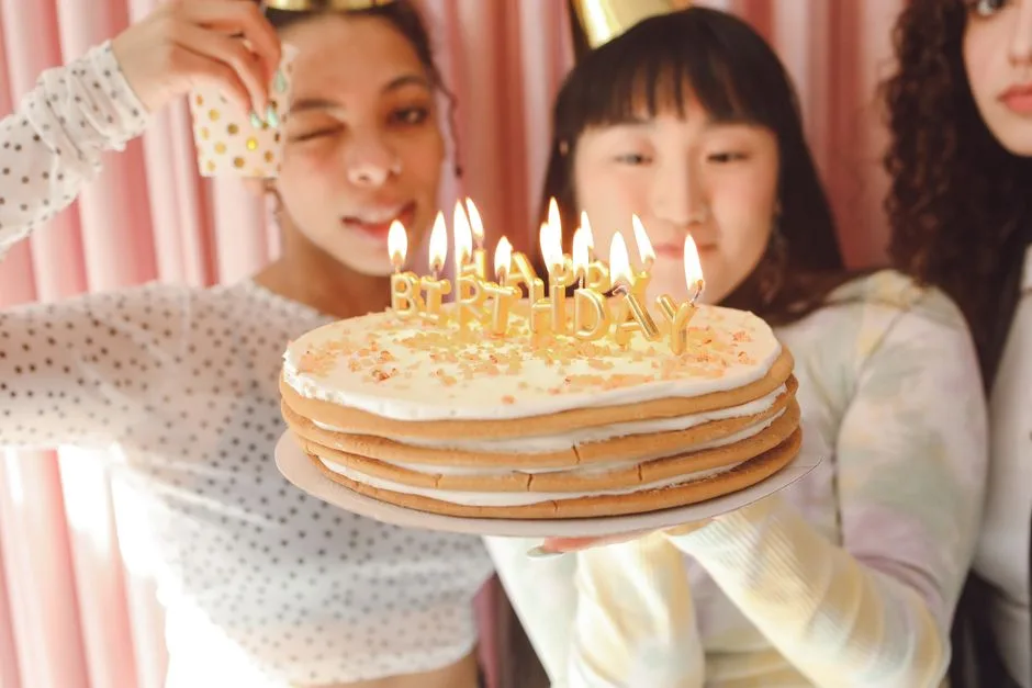 A joyful birthday party scene with teenagers holding a cake with lit candles.