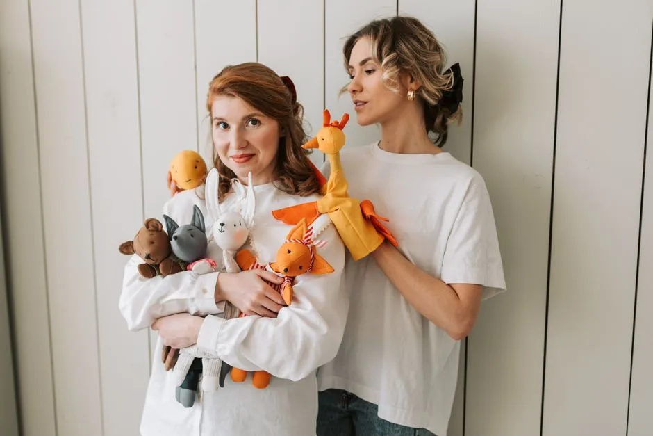 Two joyful women indoors holding assorted colorful plush toys, expressing playful and fun vibes.