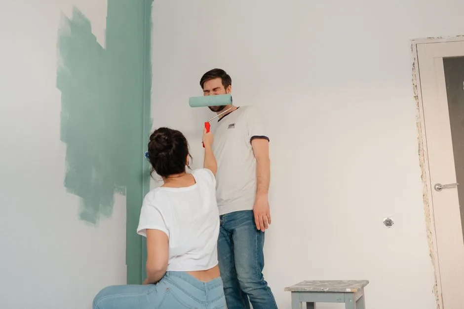 A couple collaborating to paint a room in light colors, focusing on teamwork and home improvement.