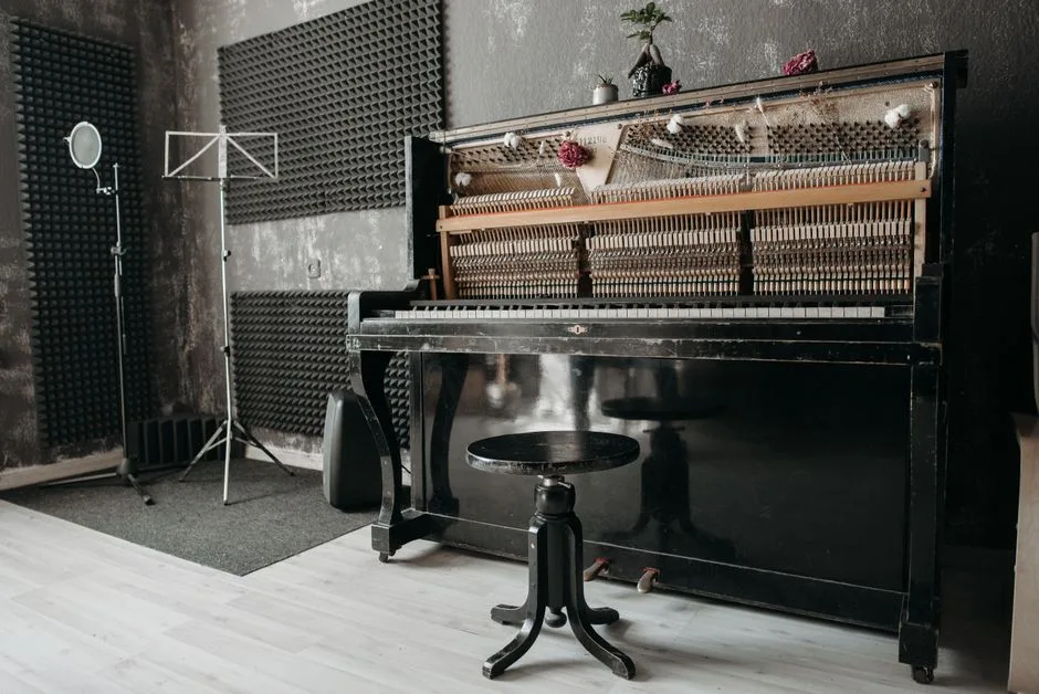An open vintage upright piano in a soundproof music studio with recording equipment.