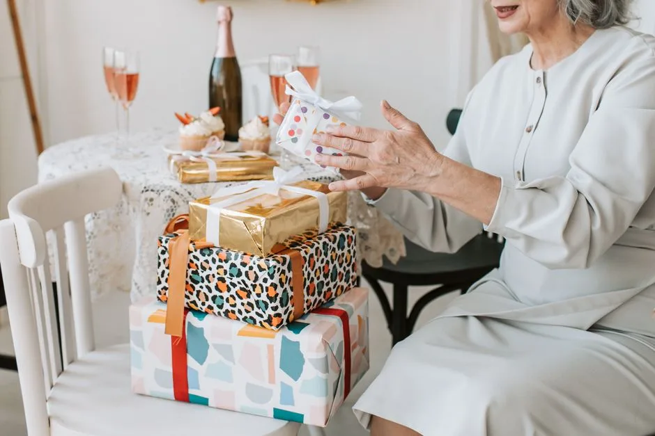 A senior woman enjoys a celebration with beautifully wrapped gifts and elegant decor.