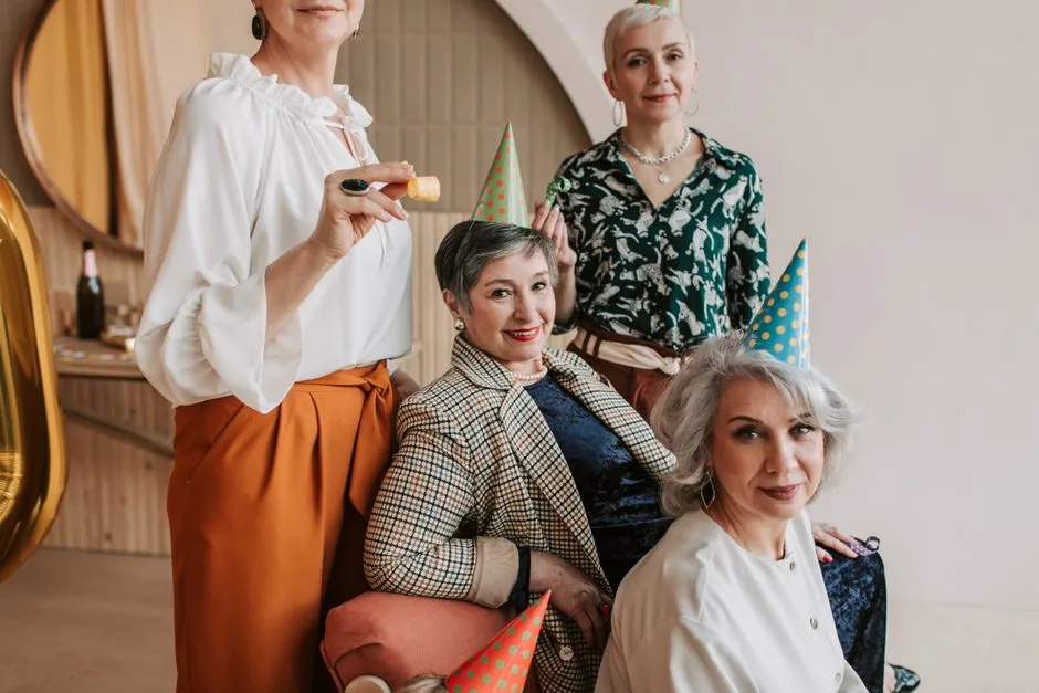 Group of senior women celebrating indoors with party hats and decorations.