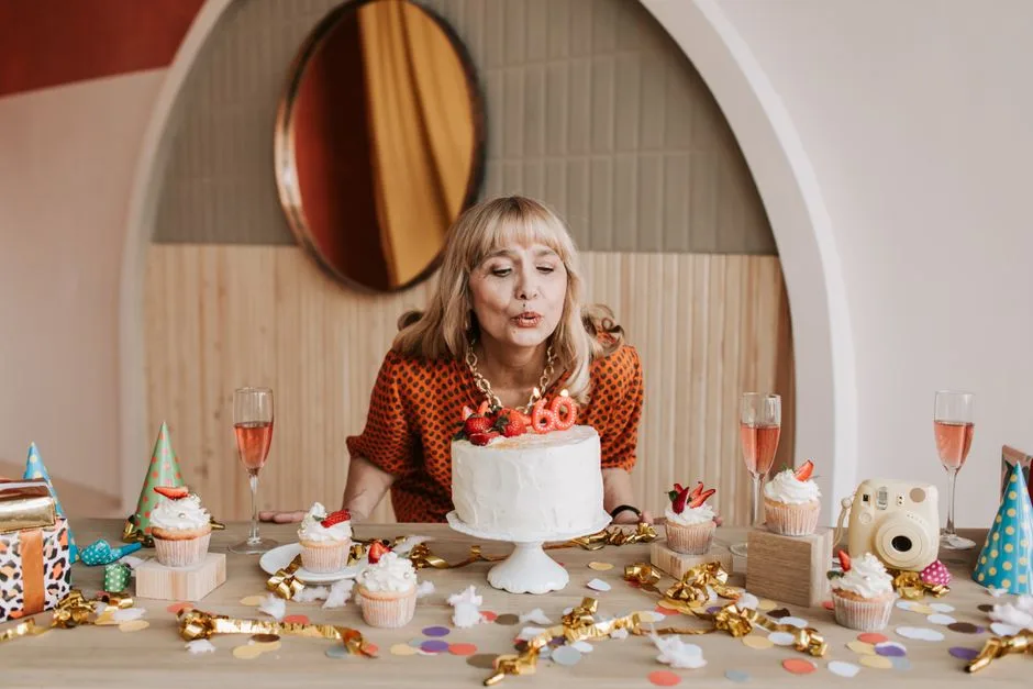 Elderly woman blowing out candles on her 60th birthday cake with festive decorations.