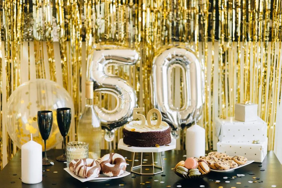 Stylish 50th birthday party setup with cake, gifts, and balloons in gold theme.