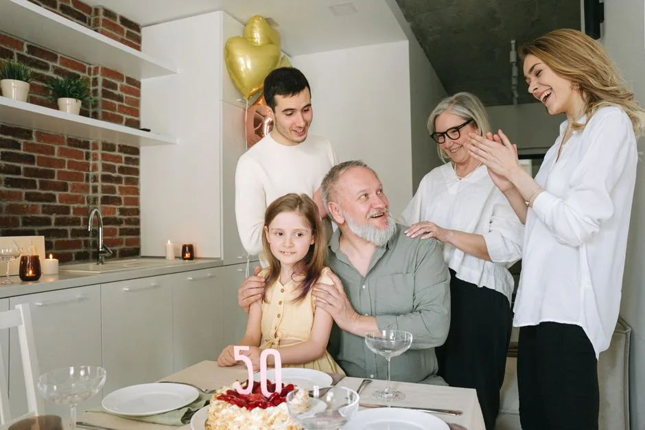 A joyful family celebration indoors with a birthday cake and balloons marking the 50th milestone.