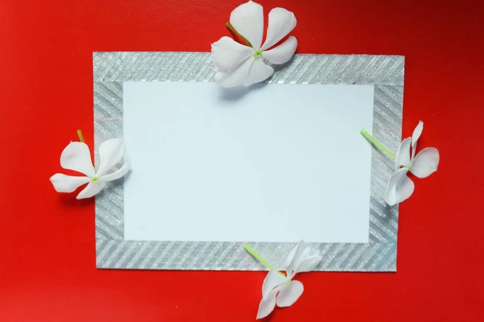 White flowers frame a blank card against a vivid red background, perfect for mockup use.
