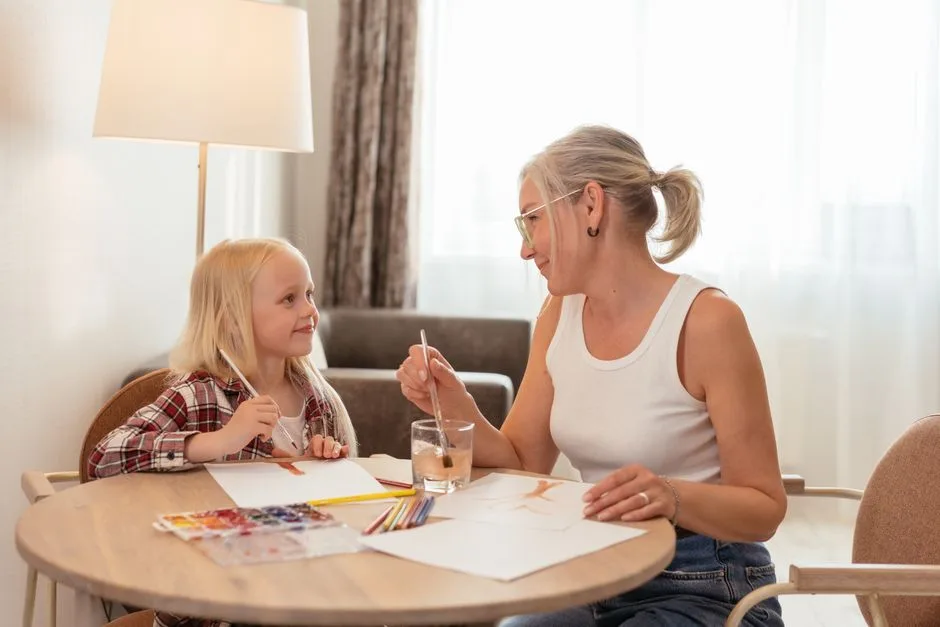 A loving moment between a grandmother and granddaughter painting at home.
