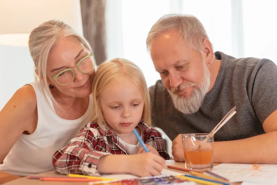 Grandparents lovingly spend time with their grandchild, nurturing creativity indoors.
