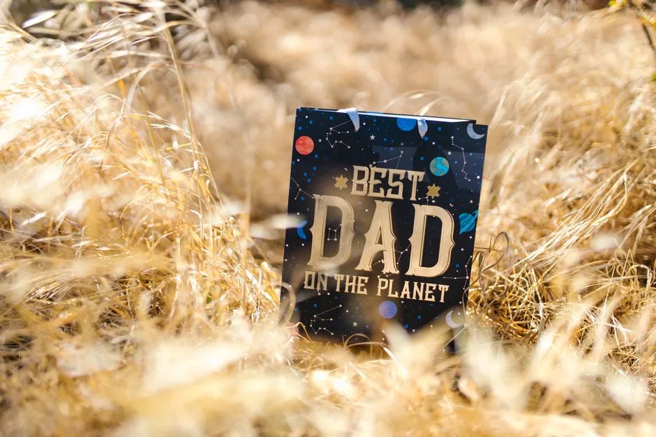 A 'Best Dad on the Planet' card amidst a field of dried grass, perfect for Father's Day gifts.