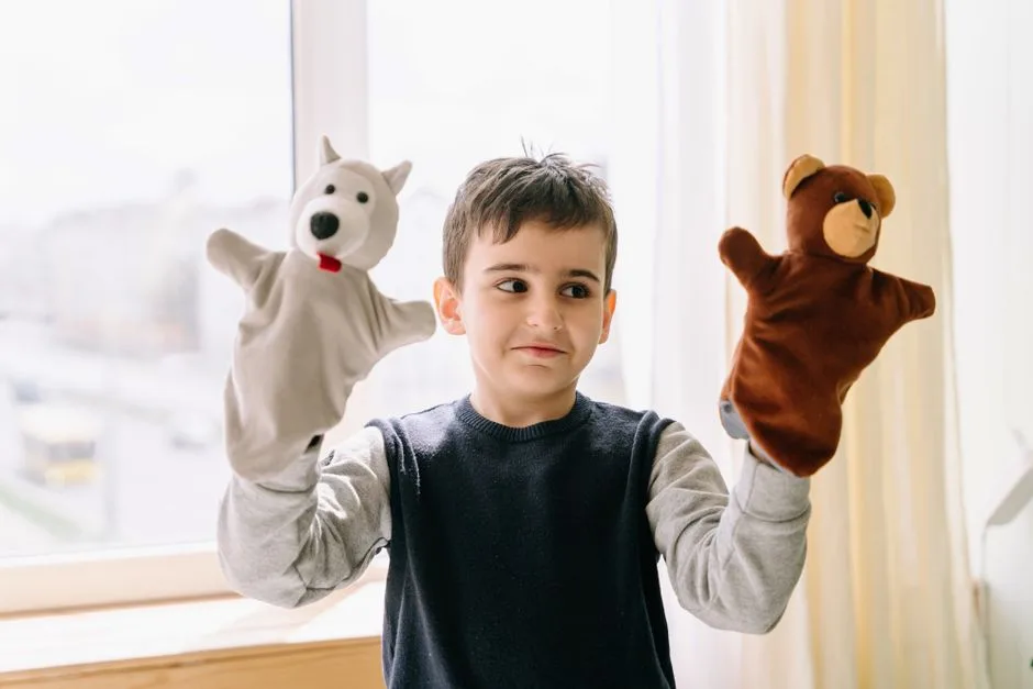 A young boy joyfully plays with bear and polar bear hand puppets indoors. Bright daylight setting.