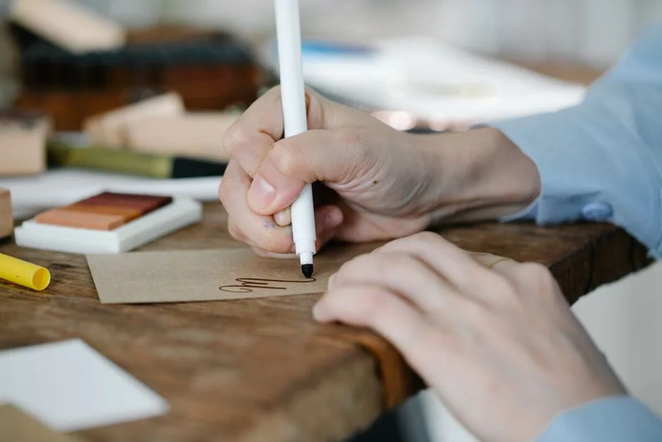A detailed close-up of a person handwriting on a card with a marker, perfect for creatives.