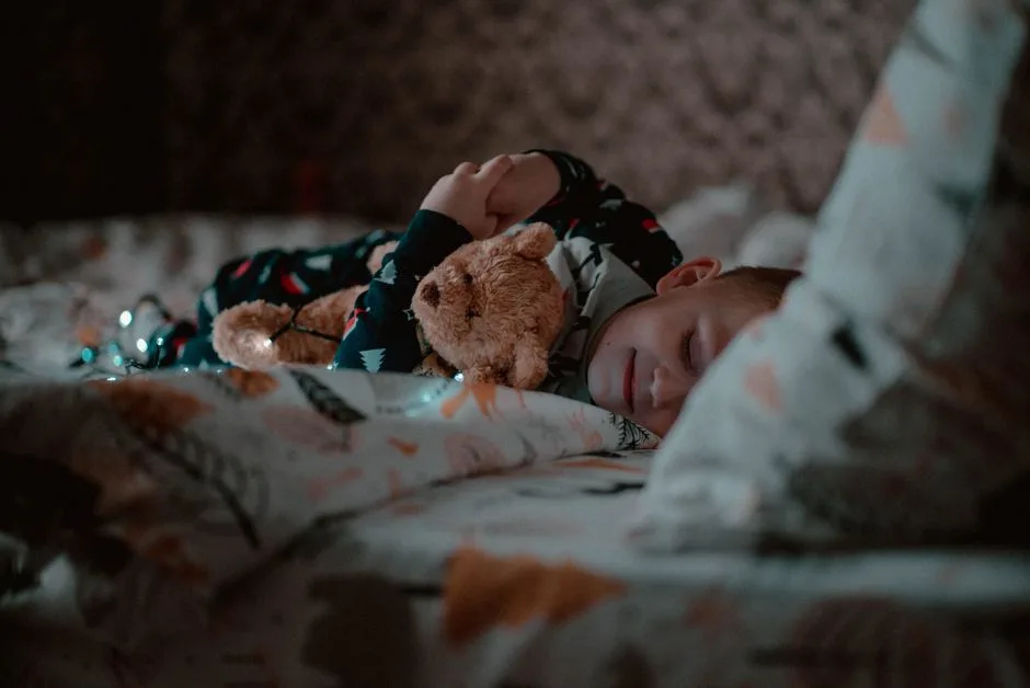 A young child peacefully sleeping in bed, hugging a teddy bear close, creating a cozy bedtime atmosphere.