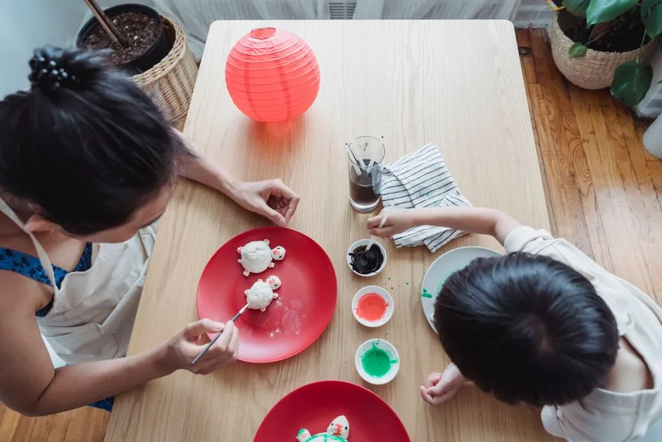 A mother and child paint crafts together in a warm home setting, fostering creativity.