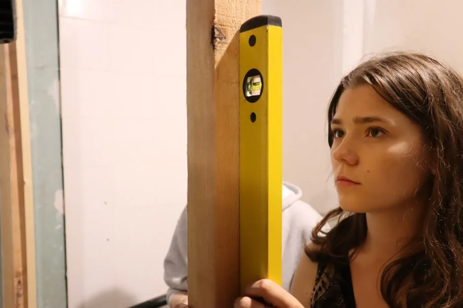 A young woman carefully using a spirit level for home improvement indoors.