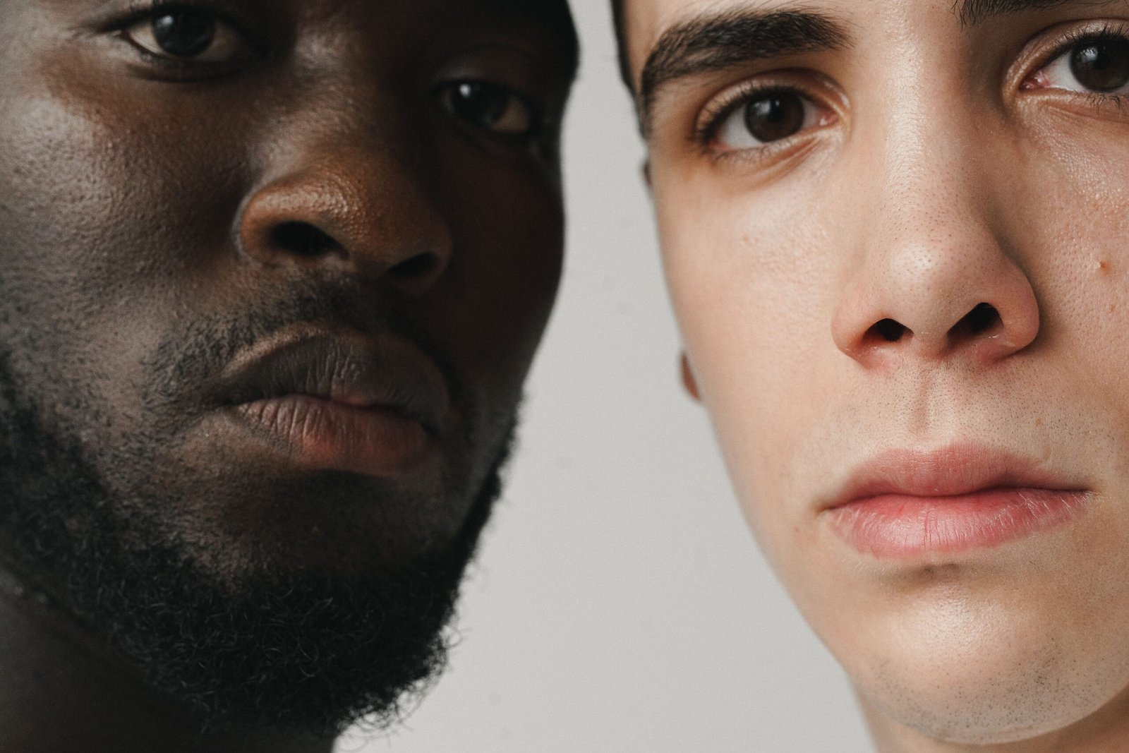 Intimate close-up portrait of two men with different ethnic backgrounds.