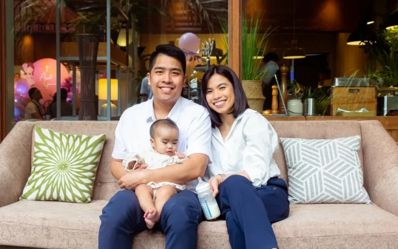 Cheerful family on a couch at home with their baby, enjoying quality time together.