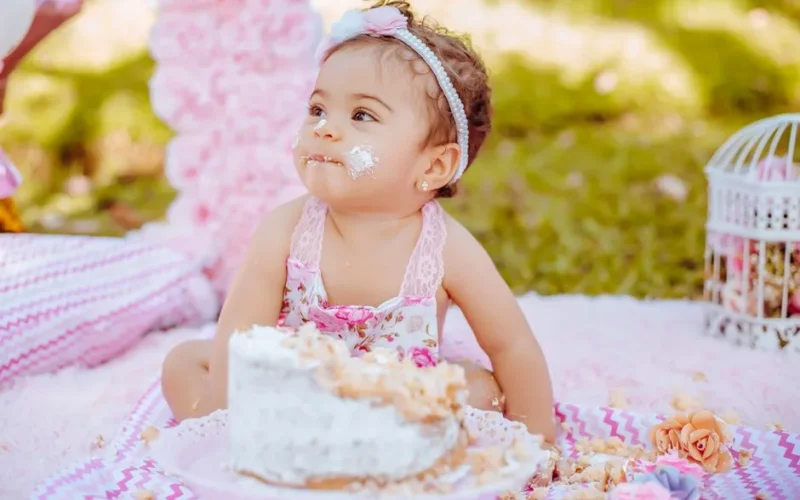 Charming scene of a baby's first cake smash outdoors with a pastel theme and floral decor.