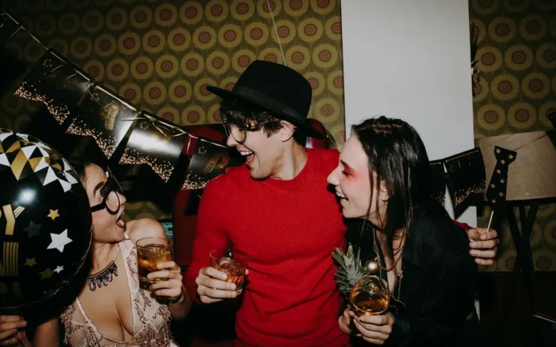 Three friends celebrate New Year's Eve with drinks and laughter.