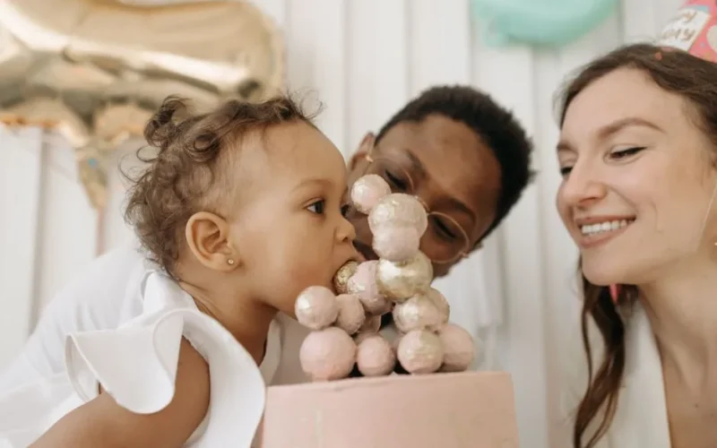 Happy family celebrating baby's first birthday with a cake.