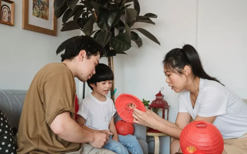 Family bonding over crafting red lanterns together in the living room.