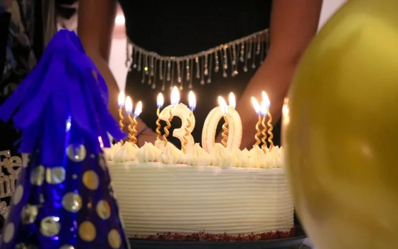 Close-up of a birthday cake with '30' candles at a festive celebration.