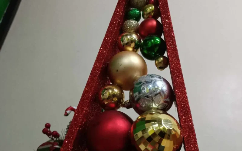 A little Christmas tree made of wood, carefully crafted with a rustic charm. The tree features small, colorful Christmas balls, adding a festive touch. Its natural wooden texture contrasts beautifully with the vibrant ornaments, creating a simple yet heartwarming holiday decoration. This miniature tree brings a cozy, handmade feel to the Christmas season.