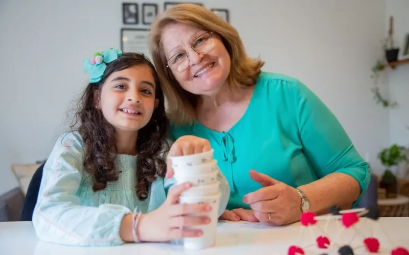 Happy grandmother and granddaughter enjoying a craft day together indoors in Portugal.