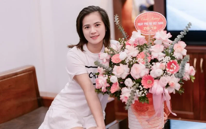 A young woman posing with a beautiful bouquet of flowers indoors, celebrating Women's Day.