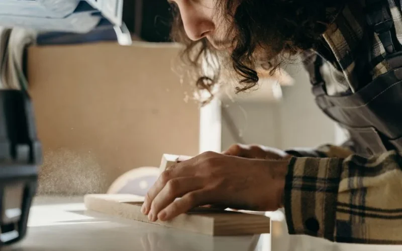 A dedicated craftsman skillfully sanding a wooden board in a cozy workshop setting.