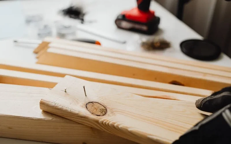 Close-up of woodworking, showing a power drill and wooden planks for DIY projects.