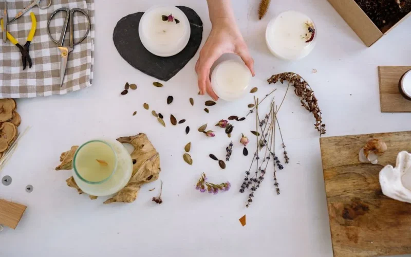Artistic candle making setup with dried flowers and crafting tools.