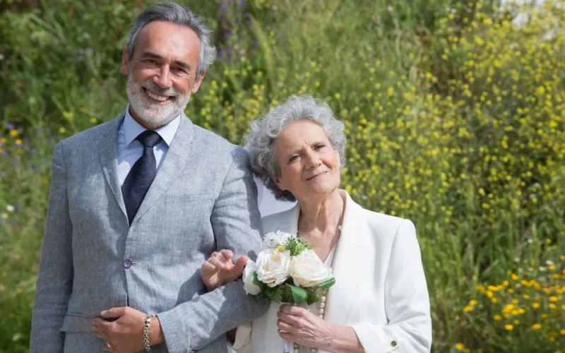 Smiling elderly couple in formal wear enjoying a beautiful day outdoors in Portugal.