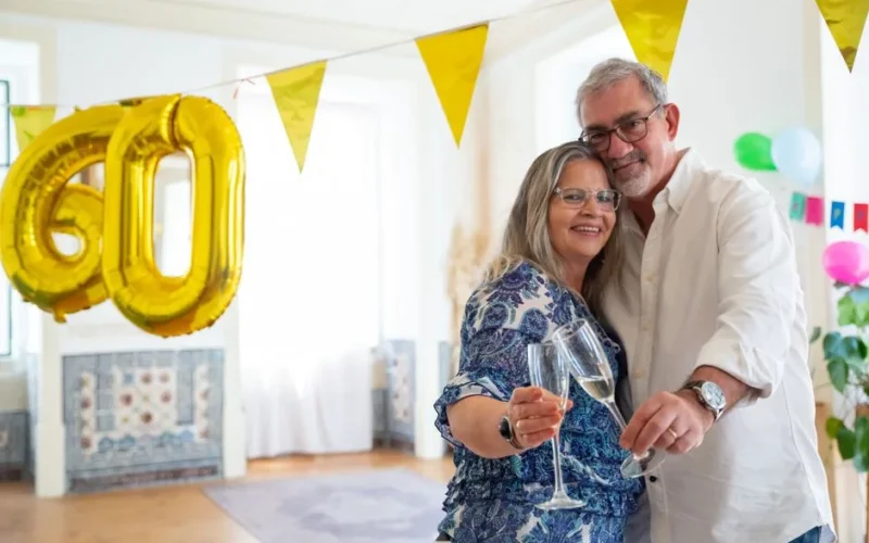 Happy elderly couple celebrating their 60th anniversary with champagne in Portugal.