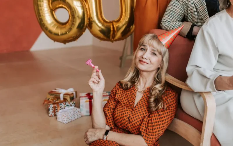 Senior woman celebrating her 60th birthday with joy and gifts indoors.
