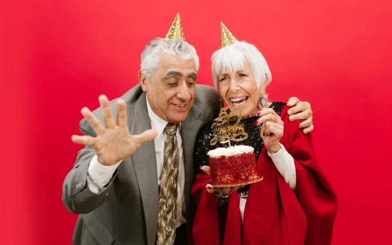 Joyful elderly couple celebrating 60th anniversary with cake and laughter.