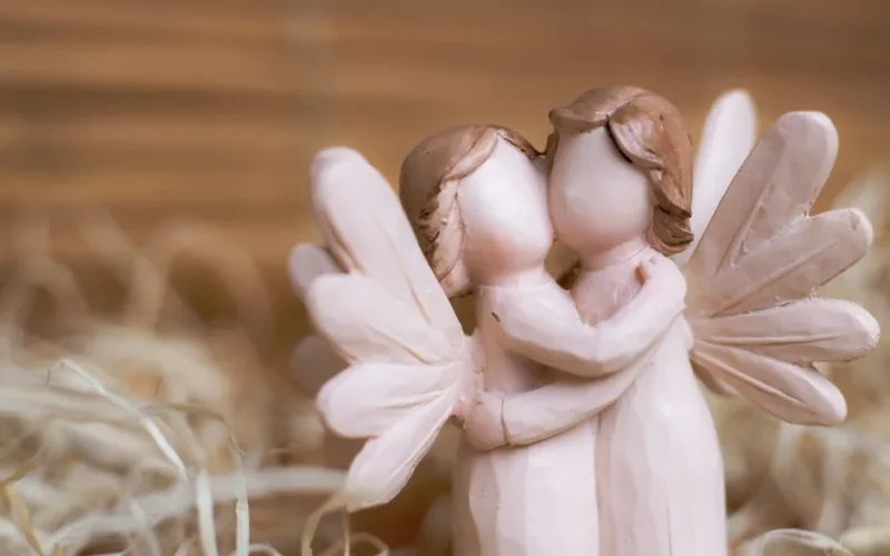 Close-up of two angelic figurines embracing in a blurred background, symbolizing love and peace.
