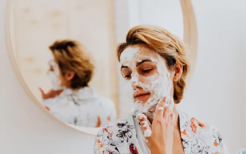 A woman enjoying a relaxing skincare routine with a facial mask in her bathroom, reflecting personal care.