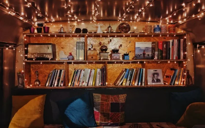 A warm and inviting reading corner with bookshelves, fairy lights, and colorful cushions.