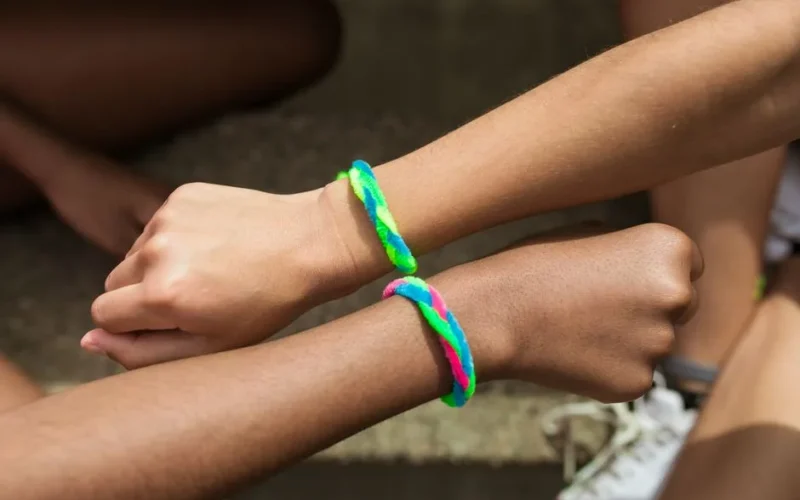 Two wrists with colorful friendship bracelets in a close-up view, symbolizing friendship.