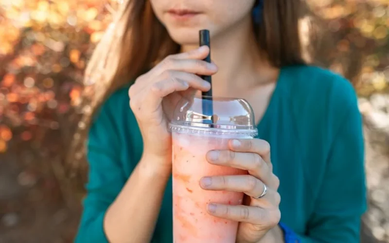 Close-up of a woman sipping bubble tea outdoors. Bright and refreshing scene.