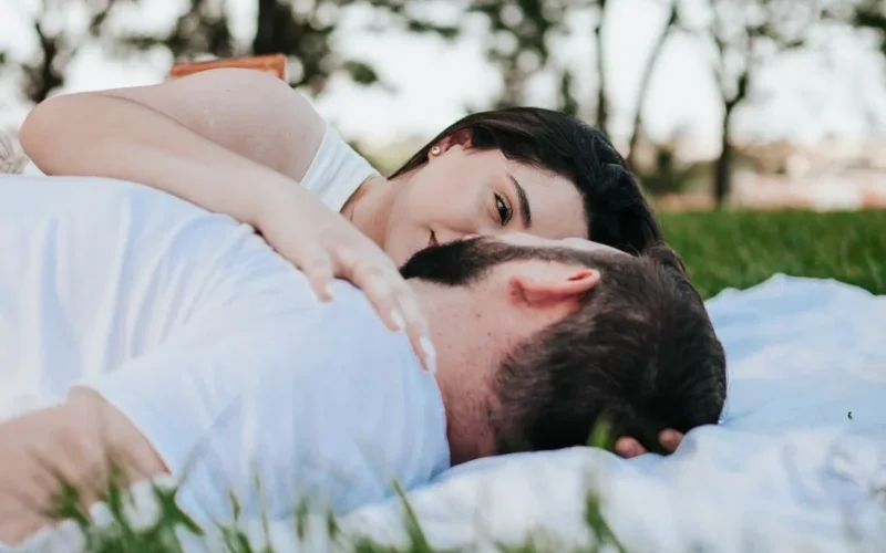 A couple relaxing on a picnic blanket outdoors, conveying love and tranquility.