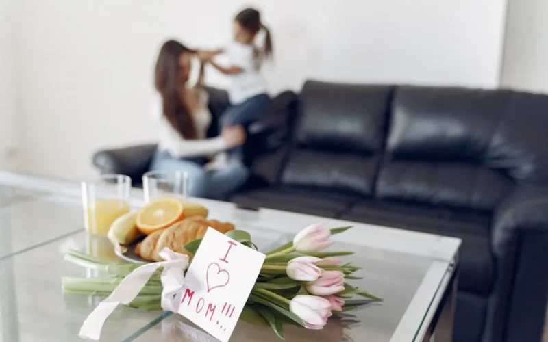Tulips and a heartfelt note on a table with a mother and child in the background.