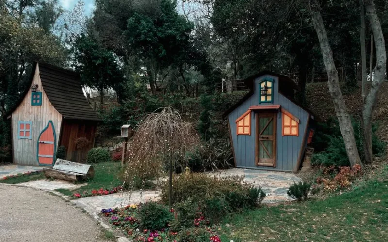 Two whimsical wooden houses nestled in a lush forest, creating a charming fairytale atmosphere.
