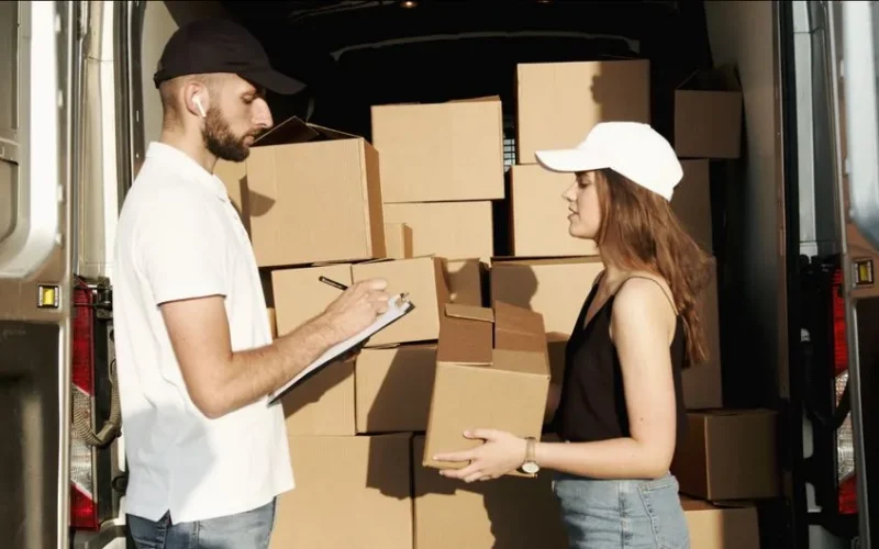 A male and female courier organizing packages in a delivery truck for efficient shipment.
