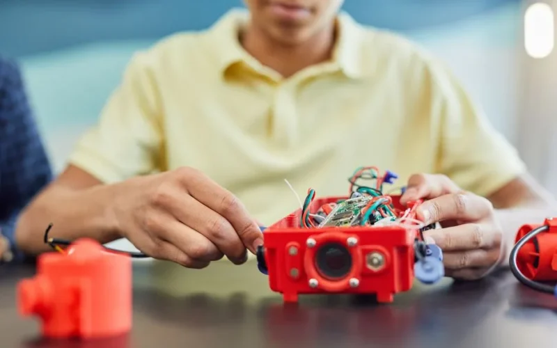 A teenager works on assembling a robotic project, showcasing innovation and creativity.