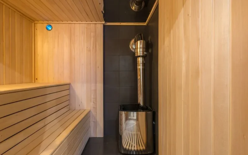 Modern wooden sauna with a sleek metal heater, showcasing luxury home interior design.