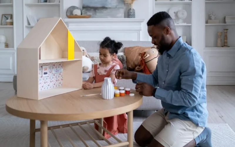 Father and daughter enjoy bonding while painting in a cozy living room setting.