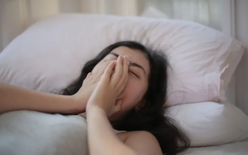 A serene scene of a woman resting in bed, displaying relaxation and comfort.
